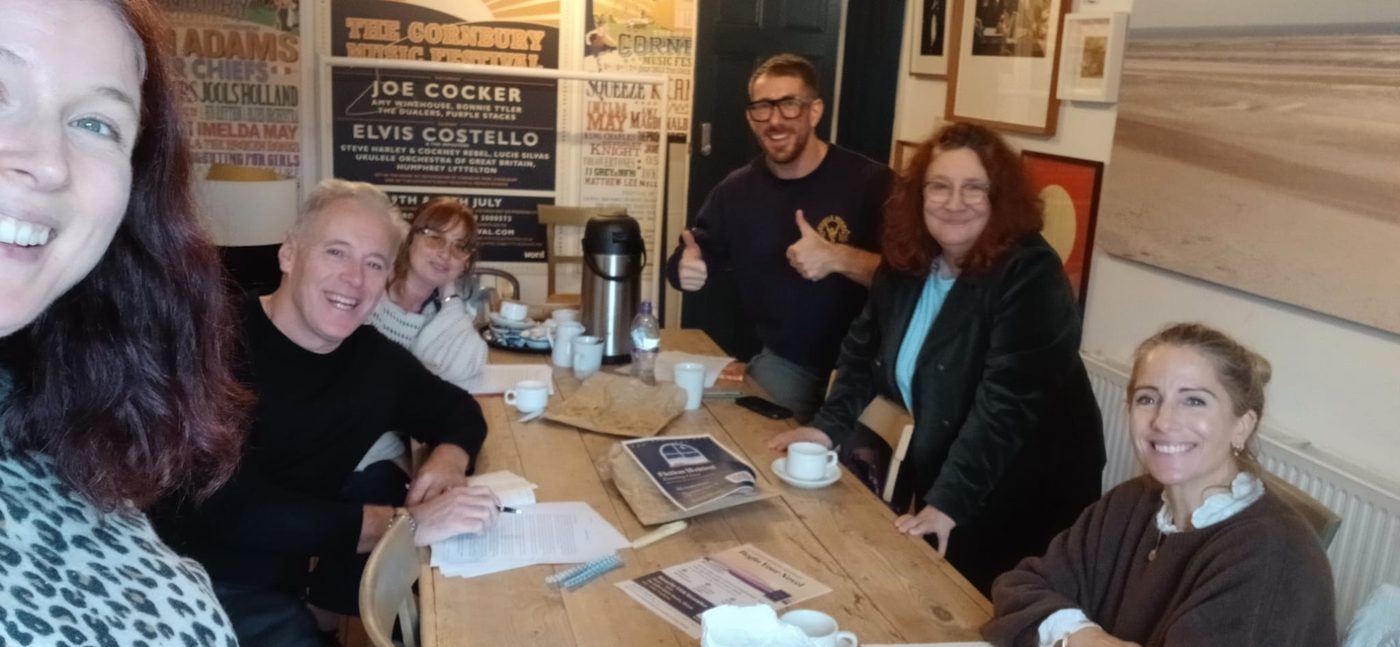 Eleanor's writing group smiling around a table in Stroud